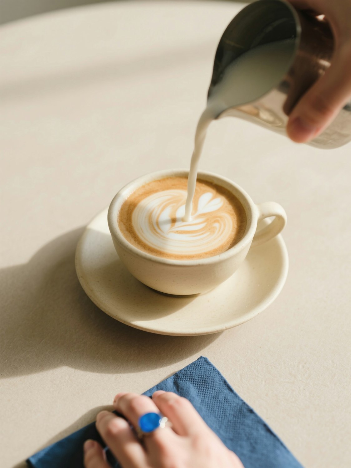 Barista pouring latte art in a warm, cozy coffee shop